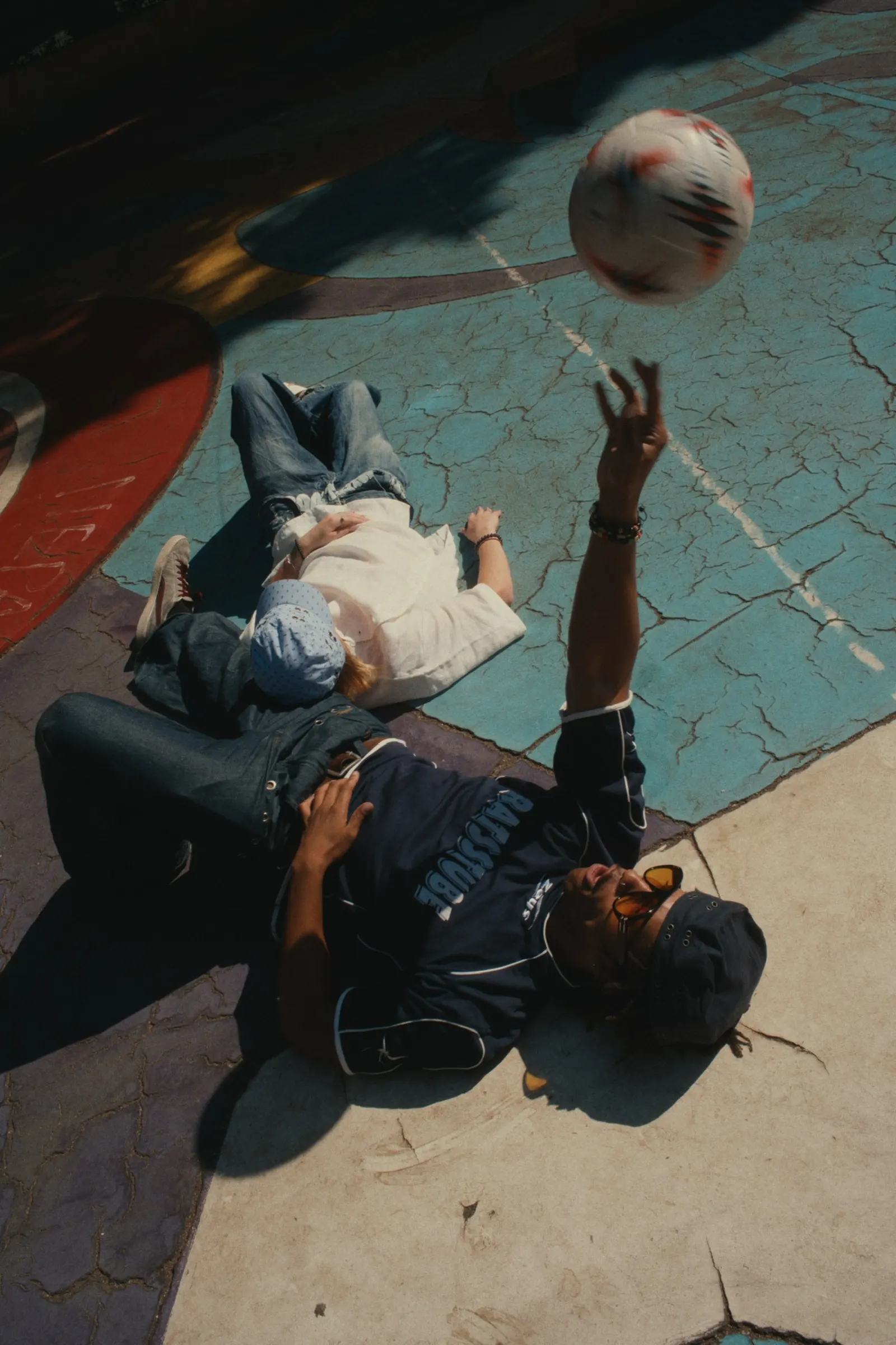Two people lying on the court, one throwing a ball into the frame